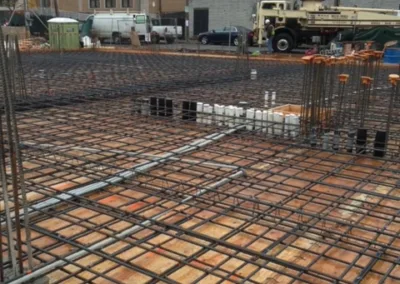 Construction site with steel reinforcement bars set up for concrete foundation work.