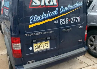 A parked black van with "sra electrical contractors" and contact information decals on the rear doors.