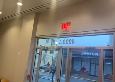 Interior view of a lobby with double doors marked as an exit under a lit exit sign.