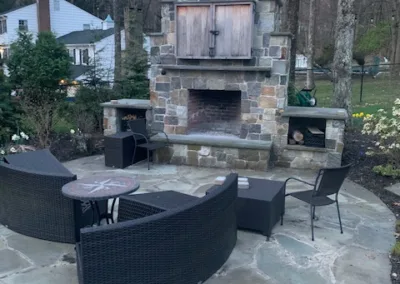 Outdoor patio with stone fireplace and curved wicker seating.